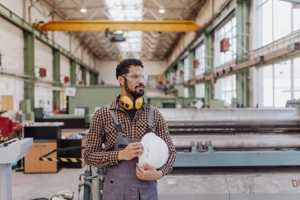 Heavy industry worker with safety headphones and hard hat in industrial factory