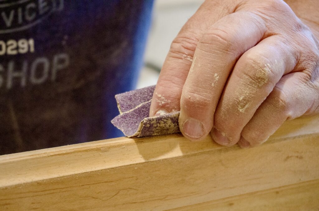 Closeup of manually sanding of wood with sandpaper